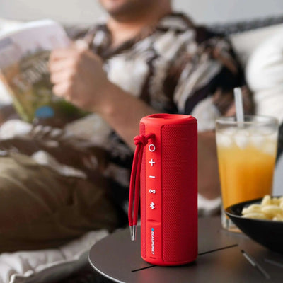 roter Bluetooth Lautsprecher BT 214 mit TWS, kompakt, robust, wassergeschützt und kabellos, auf Tisch neben Getränk und Snacks
