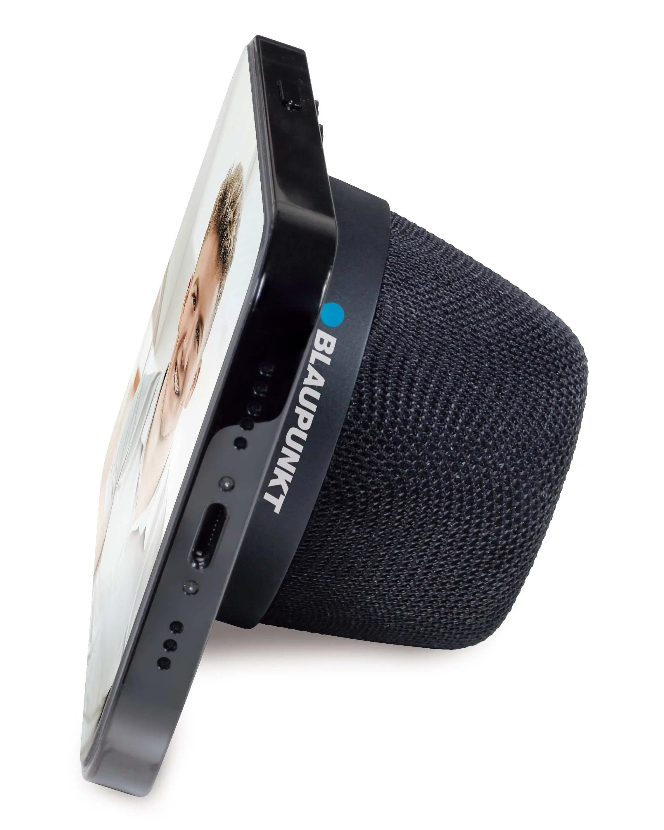 BTM 10 Bluetooth-Lautsprecher mit seitlich angelehntem Smartphone, das magnetisch als Ständer gehalten wird.