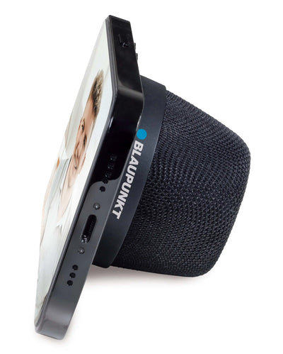 BTM 10 Bluetooth-Lautsprecher mit seitlich angelehntem Smartphone, das magnetisch als Ständer gehalten wird.