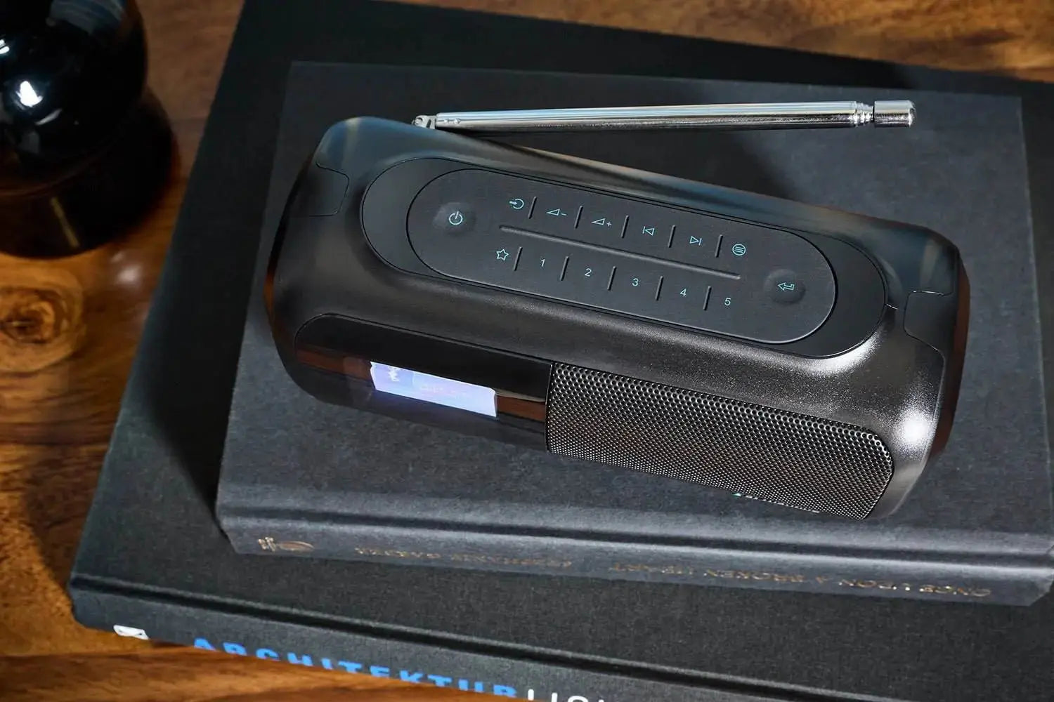 Schwarzes DAB Radio Bluetooth mit Teleskopantenne und Digitaldisplay auf Büchern