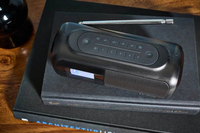 Schwarzes DAB Radio Bluetooth mit Teleskopantenne und Digitaldisplay auf Büchern