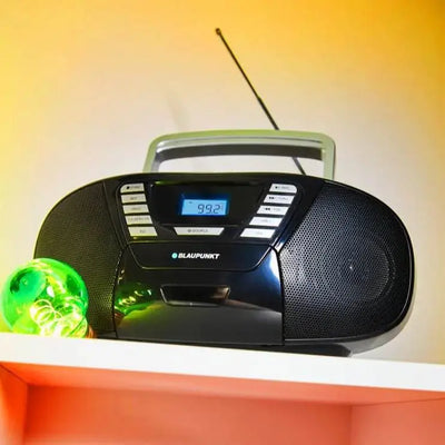 Schwarze Boombox mit CD-Player, Radio und Bluetooth von Blaupunkt auf Regal mit gelbem Hintergrund