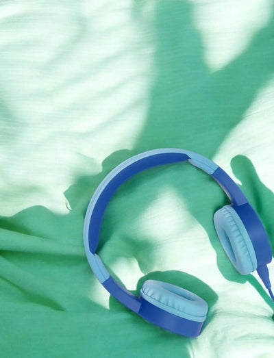 blauer Kids Kopfhörer mit Lautstärkebegrenzung und KidsSafe-Technologie auf grünem Stoff Hintergrund